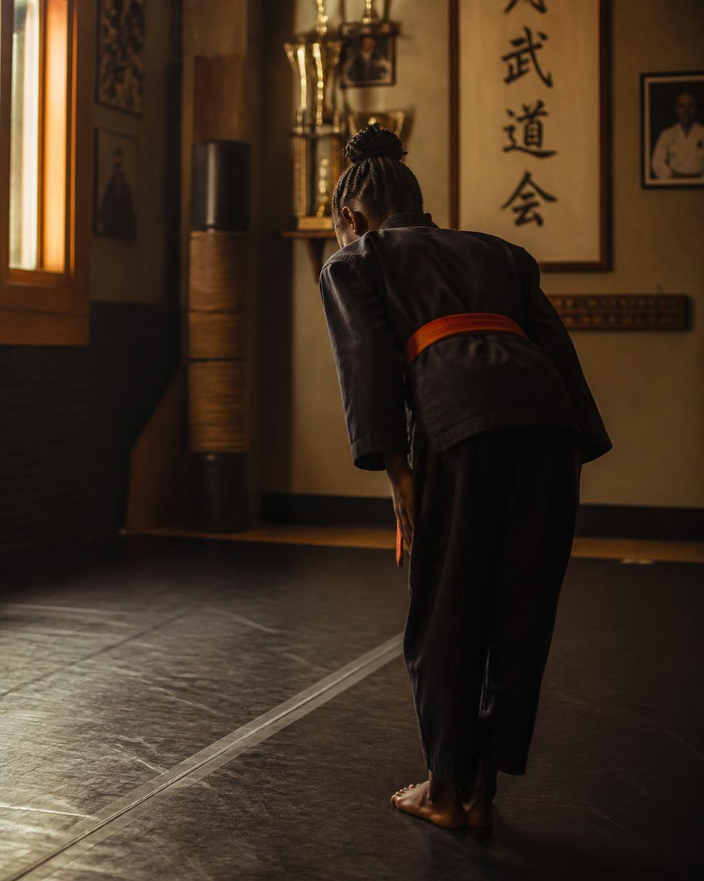 Young student bowing at the edge of the dojo mat